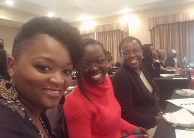Three people smiling at a conference table.