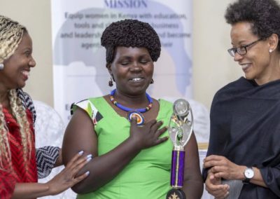 Three women celebrating with a trophy.